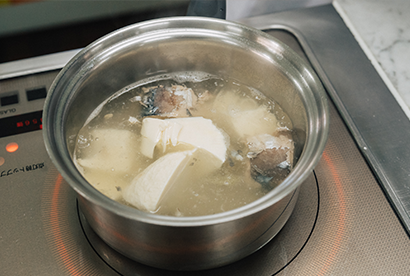 水を火にかけ、サバ水煮、豆腐を加える。調味料とわかめを加えた後、とろみをつける。